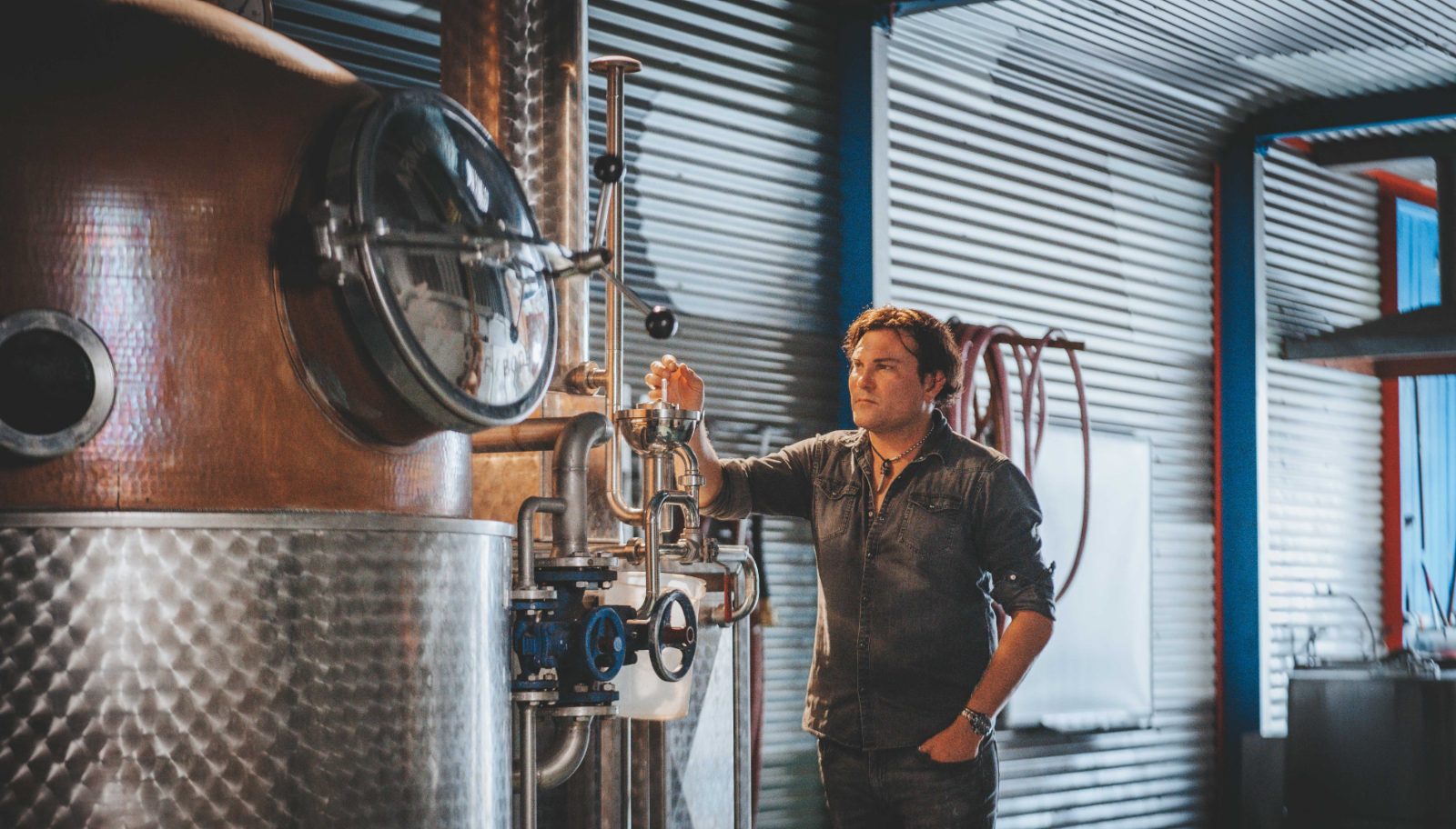 Head distiller Mark Watkins at Helga, the copper pot still, taking a reading from the spirit safe